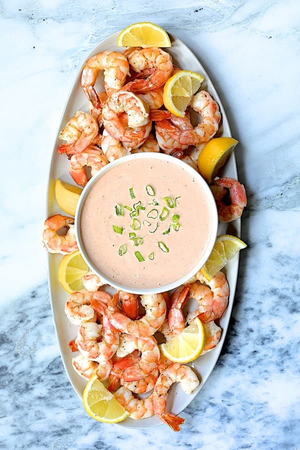 Photo of Shrimp Cocktail Louis on white oval platter garnished with lemon wedges.
