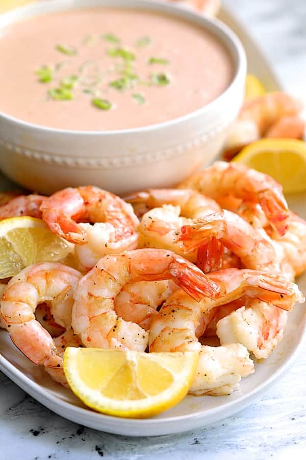 Close-up photo of Shrimp Cocktail Louis on white platter with sauce in the background.