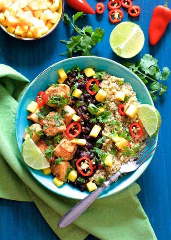 Cuban Chicken and Black Bean Quinoa Bowls garnished with lime wedges and cilantro.