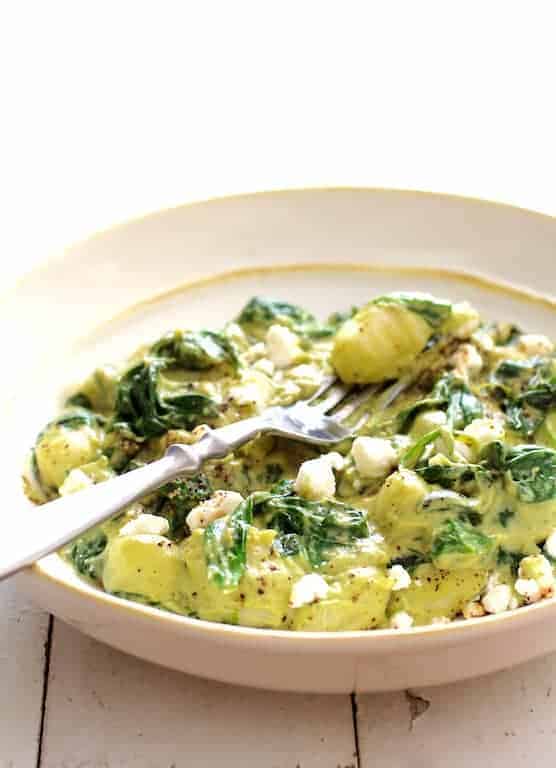 Gnocchi with Spinach and Avocado Goat Cheese Sauce in white bowl.