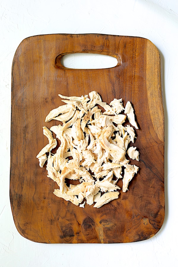 Photo of shredded chicken on rustic wood cutting board.