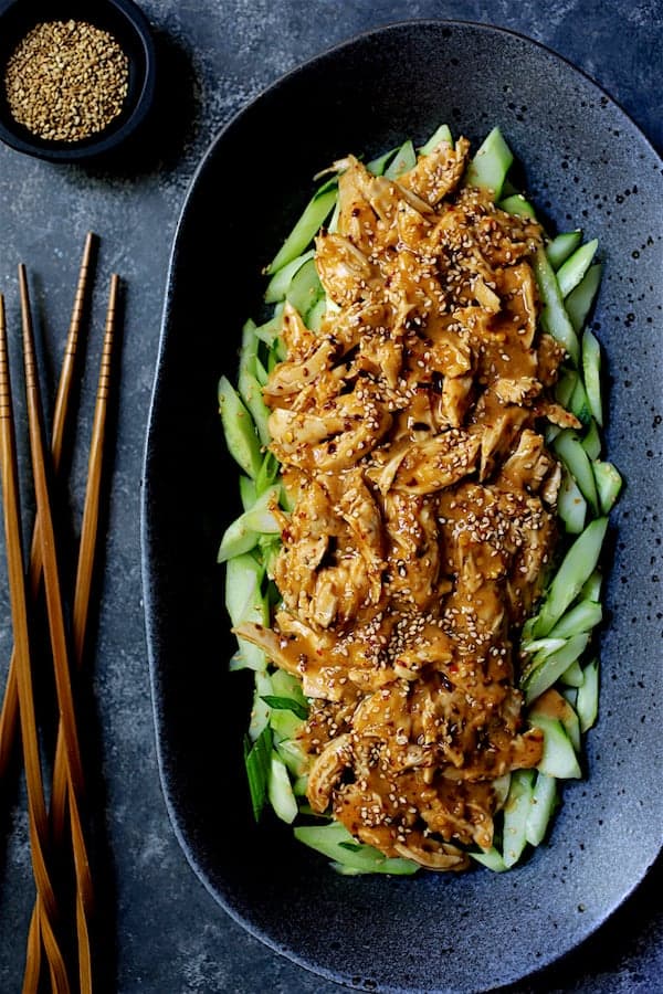 Close-up photo of Sichuan Bang Bang Chicken on black oval platter garnished with sesame seeds.