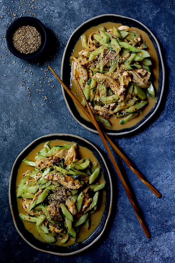 Photo of Sichuan Bang Bang Chicken on two oval dishes with chopsticks garnished with sesame seeds.
