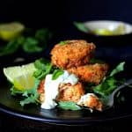Thai Salmon Cakes with Basil - Lime Mayonnaise on black plate.