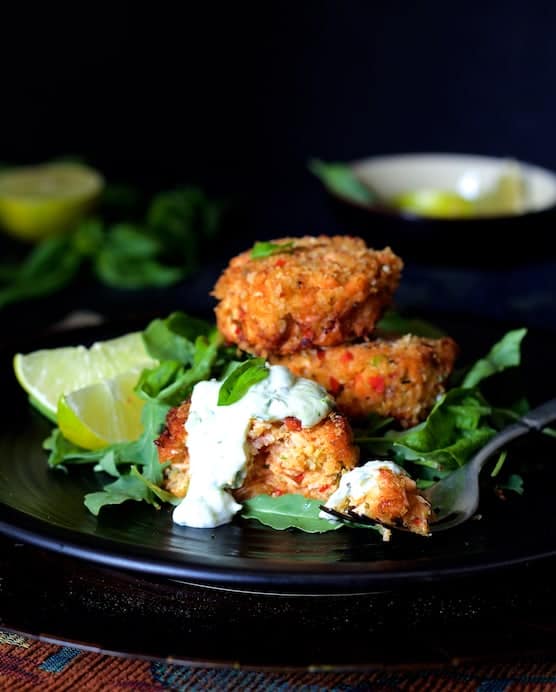 Thai Salmon Cakes with Basil - Lime Mayonnaise on black plate.