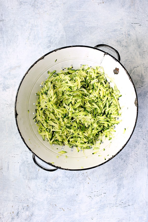 Photo of shredded zucchini in white colander.
