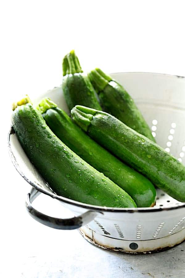 Photo of five fresh zucchini in white colander.