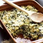 Cheesy Brown Rice and Greens Casserole in a brown rectangular baking dish with wooden spoon.