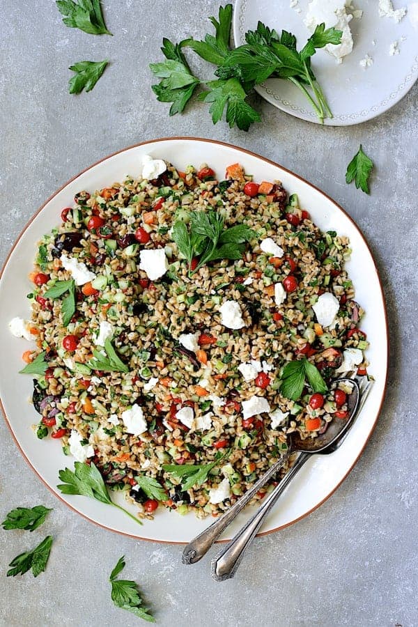 Photo of Mediterranean Farro Salad on round white platter garnished with parsley.