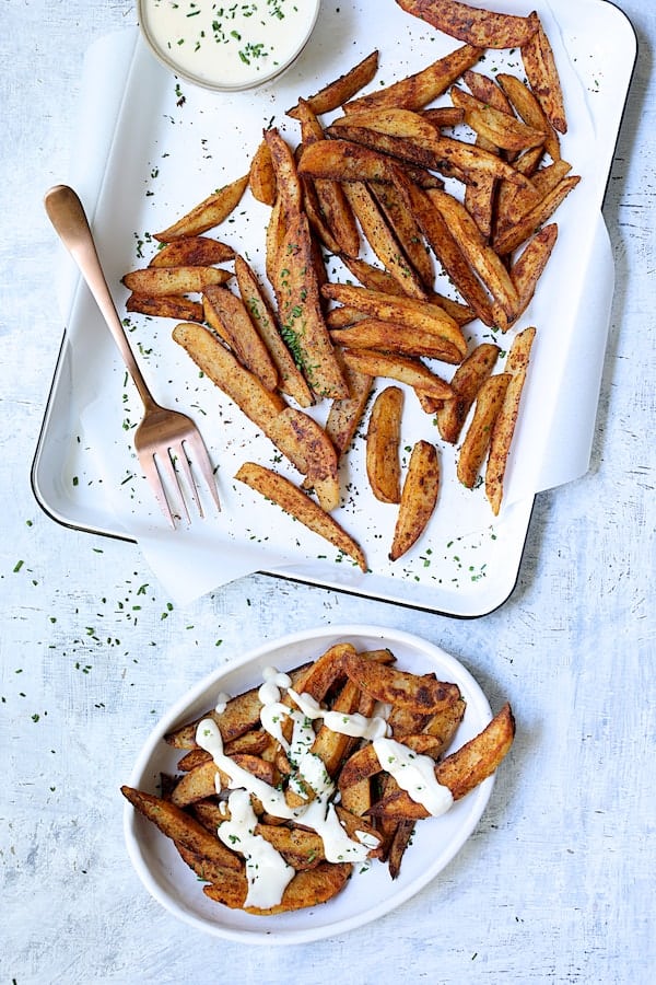 Photo of Old Bay Roasted Potato Wedges with Vermont Cheddar Cheese Sauce with some served up in white oval bowl.