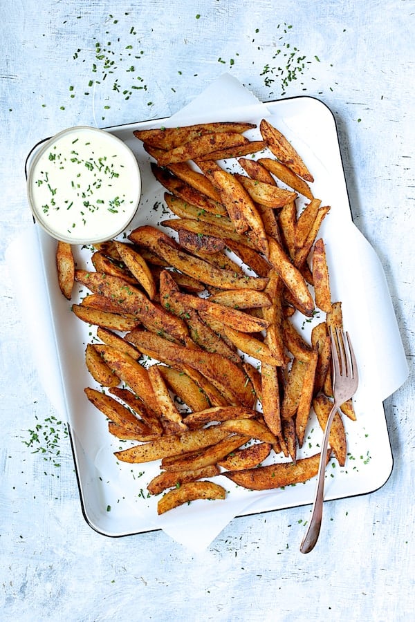 Photo of Old Bay Roasted Potato Wedges with Vermont Cheddar Cheese Sauce garnished with fresh chives.