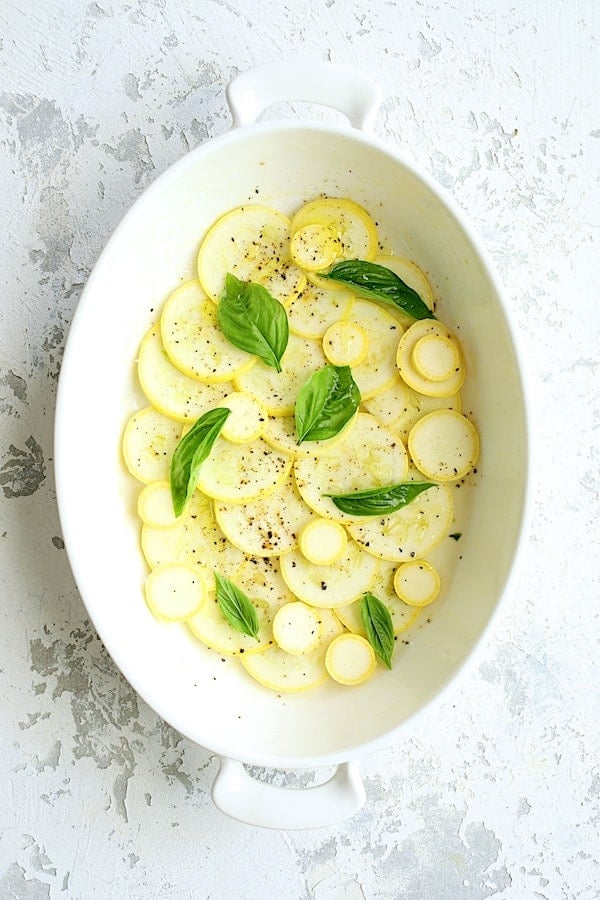 Photo of the first layer of yellow squash in white gratin dish.