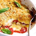Yellow Squash and Tomato Gratin in oval white baking dish with piece removed.