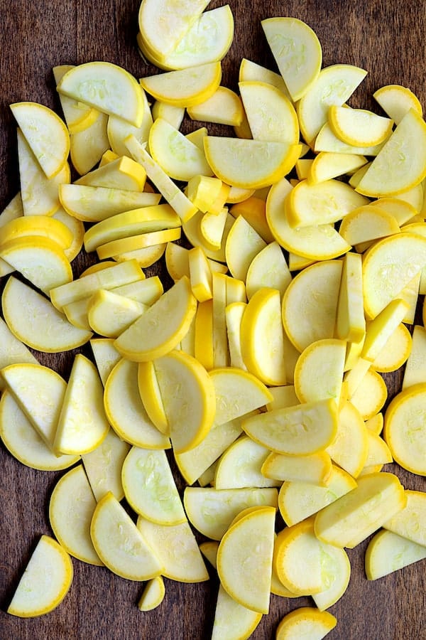 Photo of half-moon sliced yellow squash on cutting board.