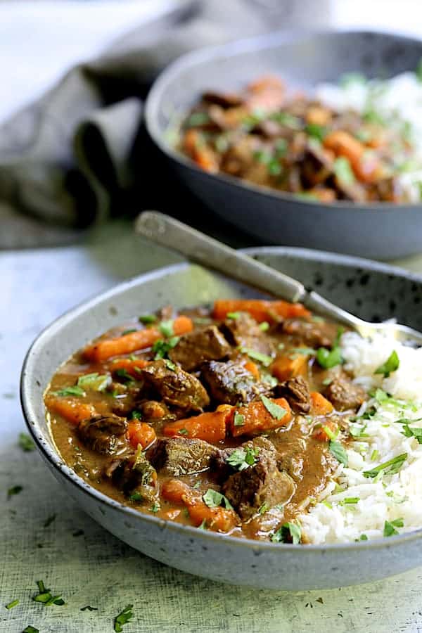 Photo of Pressure Cooker Indian Curry Beef Stew in gray bowls with white basmati rice.