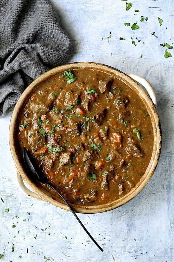 Photo of Pressure Cooker Indian Beef Curry Stew on pale blue background with gray napkin.