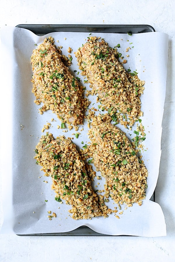 Walnut-Crusted Chicken with Pomegranate Sauce - Overhead shot of chicken breasts coated with walnuts on parchment paper before baking
