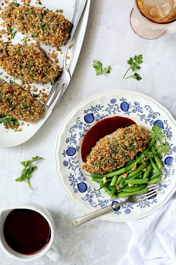 Walnut-Crusted Chicken with Pomegranate Sauce - Overhead shot with one breast served up on blue and white plate with sauce and green beans