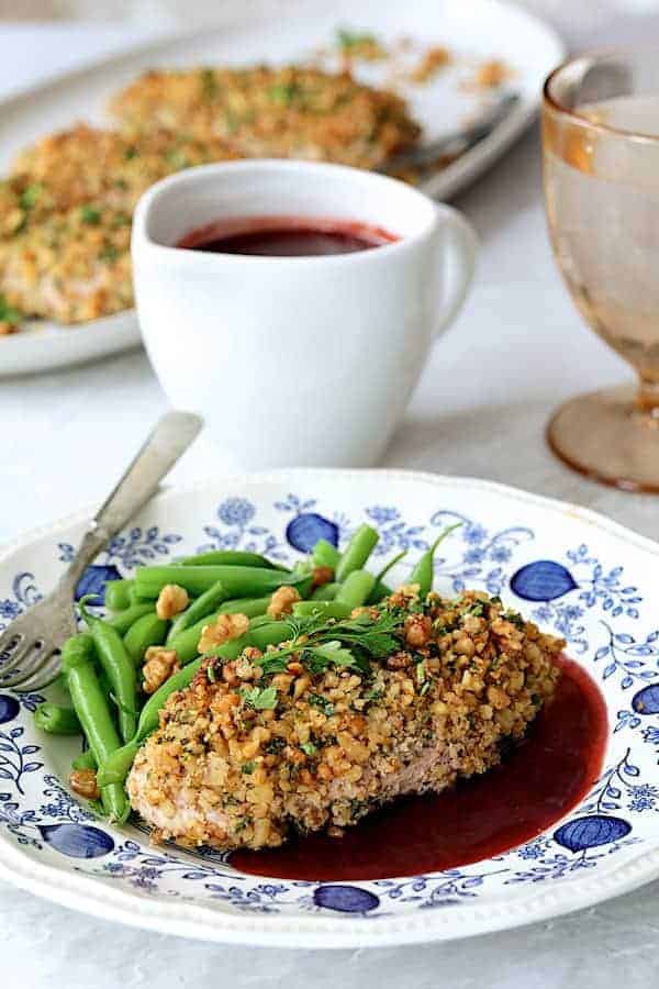 Walnut-Crusted Chicken with Pomegranate Sauce - Close-up straight-on shot of chicken on blue and white plate with green beans