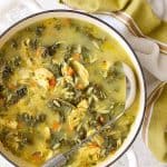 Cold-Fighting Chicken, Kale and Orzo Soup in white Dutch oven with soup ladle.