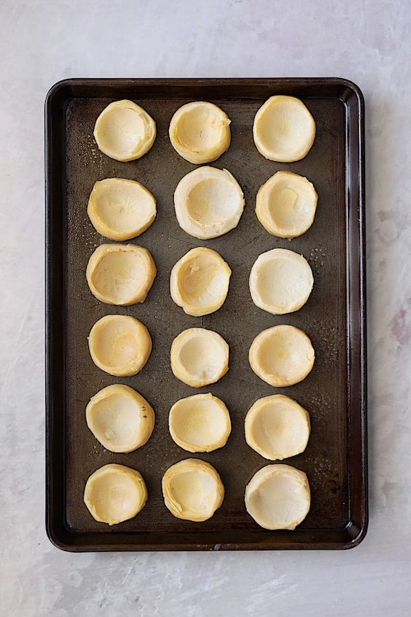 Photo of 18 artichoke bottoms on baking sheet.