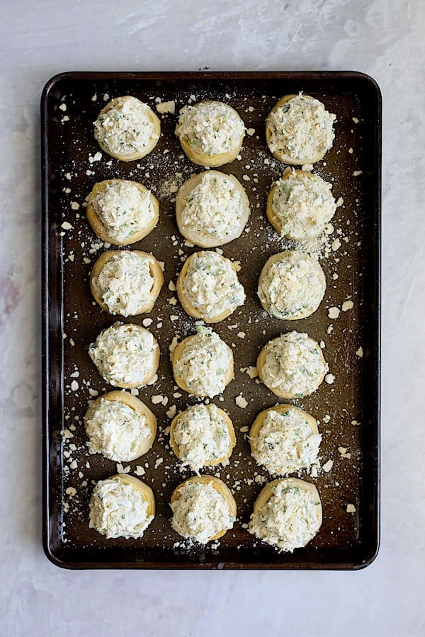 Photo of 18 filled artichoke bottoms on baking sheet.