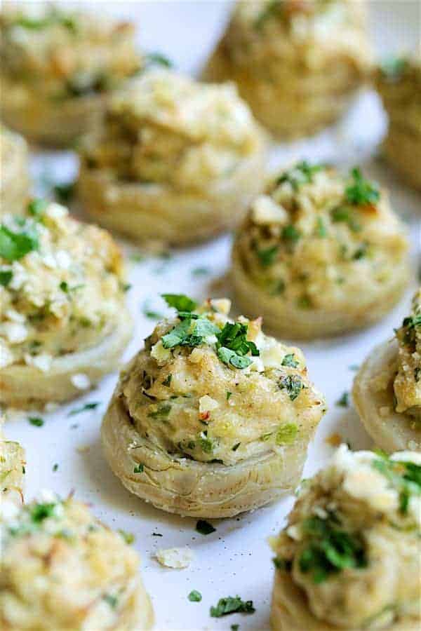 Close-up photo of Deviled Crab Stuffed Artichoke Bottoms on white platter garnished with fresh parsley.