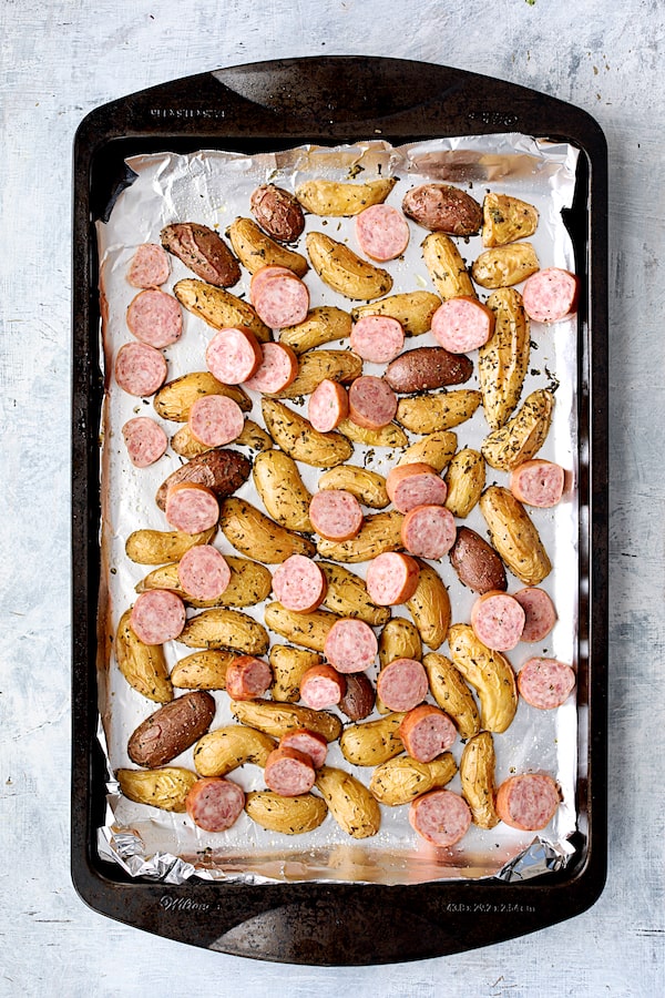 Photo of semi-roasted potatoes after adding the sausage to the sheet pan.