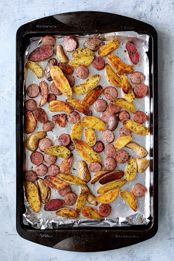 Photo of roasted potatoes and cooked sausage on sheet pan.