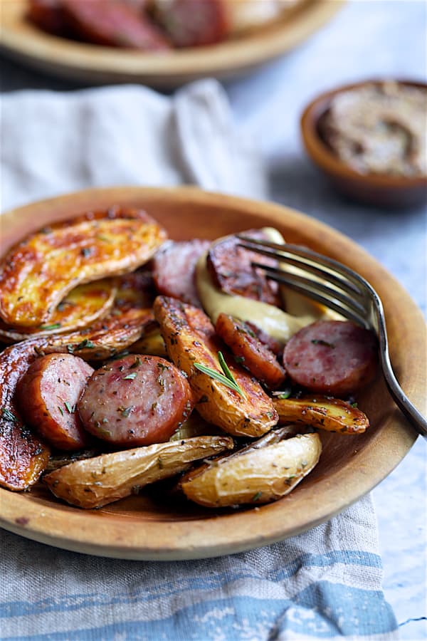 Close-up photo of Duck Fat and Rosemary Roasted Fingerling Potatoes with Sausage in wooden bowls.