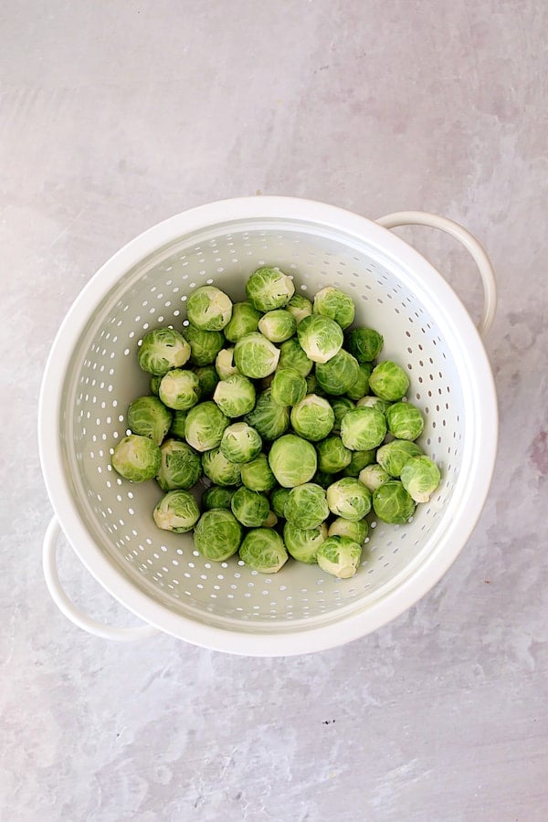 Photo of uncooked Brussels Sprouts in white colander.