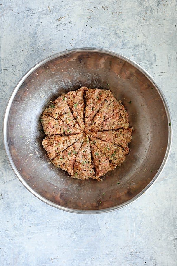Overhead shot of meat filling in stainless steel bowl divided into 12 sections