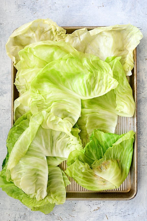 Spicy Italian Stuffed Cabbage - Overhead shot of cabbage leaves with one in the process of being folded and rolled