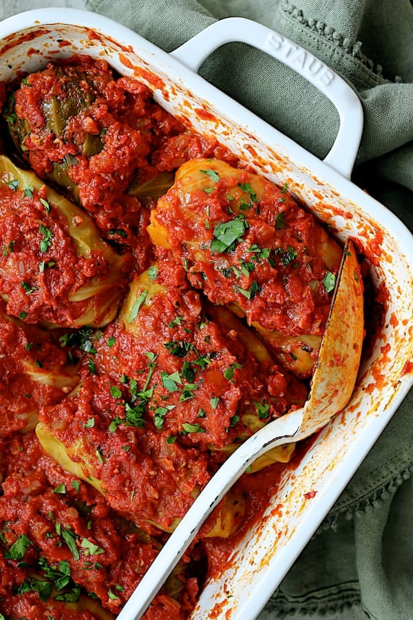 Spicy Italian Stuffed Cabbage - Close-up angled shot of baked cabbage rolls in white baking dish