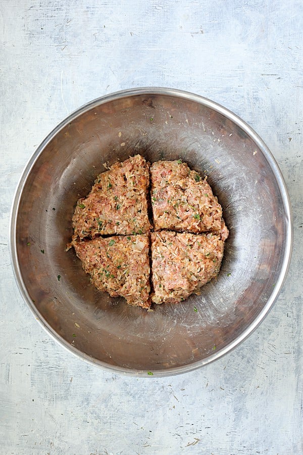 Overhead shot of meat filling in stainless steel bowl divided into four sections