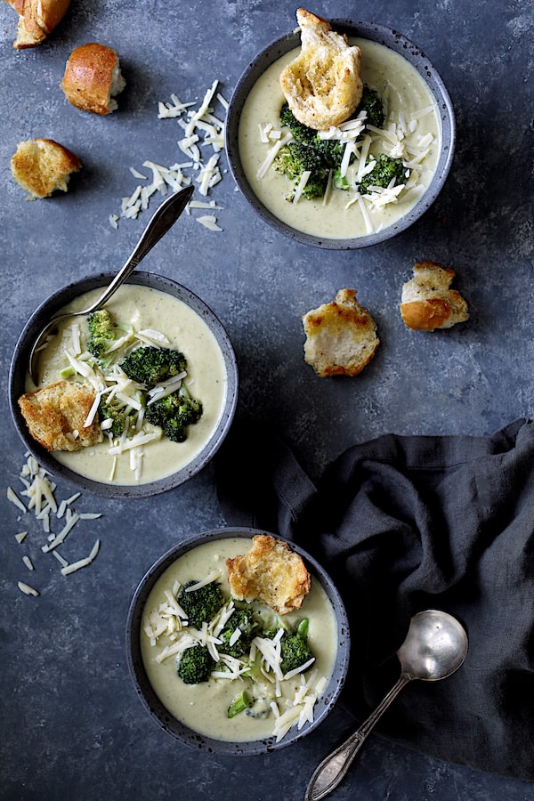 Broccoli Gruyere Soup with Torn Garlic Croutons - Overhead shot of three bowls of the soup garnished with cheese, broccoli and croutons