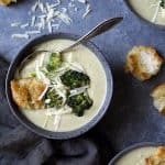 Broccoli Gruyere Soup in gray bowl with croutons garnished with broccoli florets.