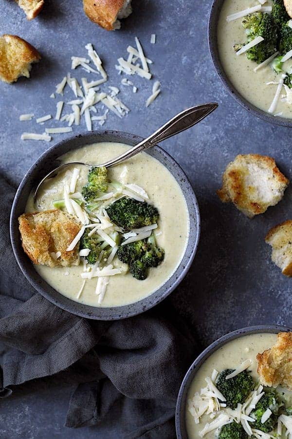 Broccoli Gruyere Soup with Torn Garlic Croutons - Overhead hero shot of soup on dark blue background