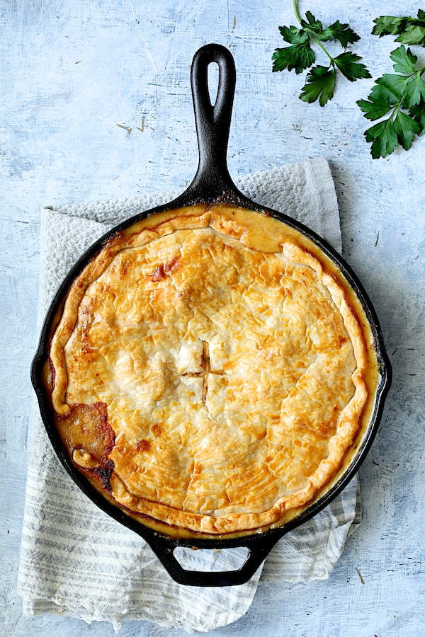 Photo of baked Cheesy Skillet Chicken Pot Pie on blue towel.