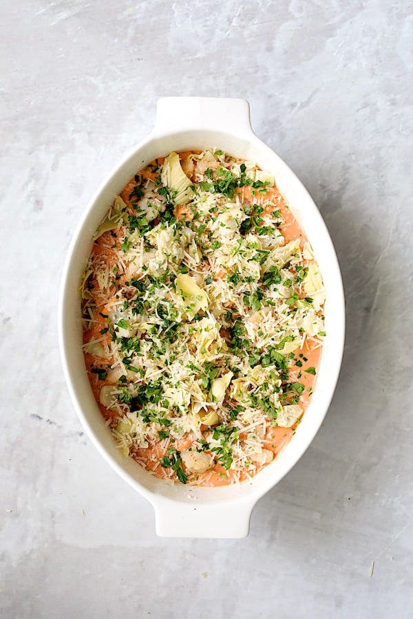 Photo of lasagna with cheese and parsley added.