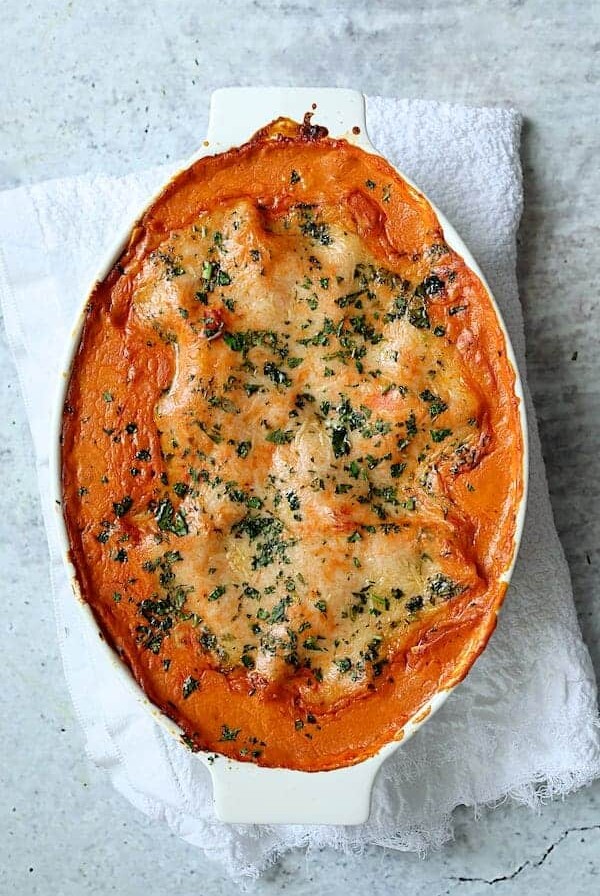 Shrimp Scallop and Artichoke Lasagna in oval white baking dish.