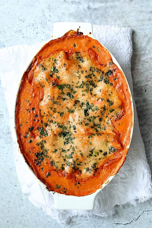 Shrimp Scallop and Artichoke Lasagna in oval baking dish on white towel.