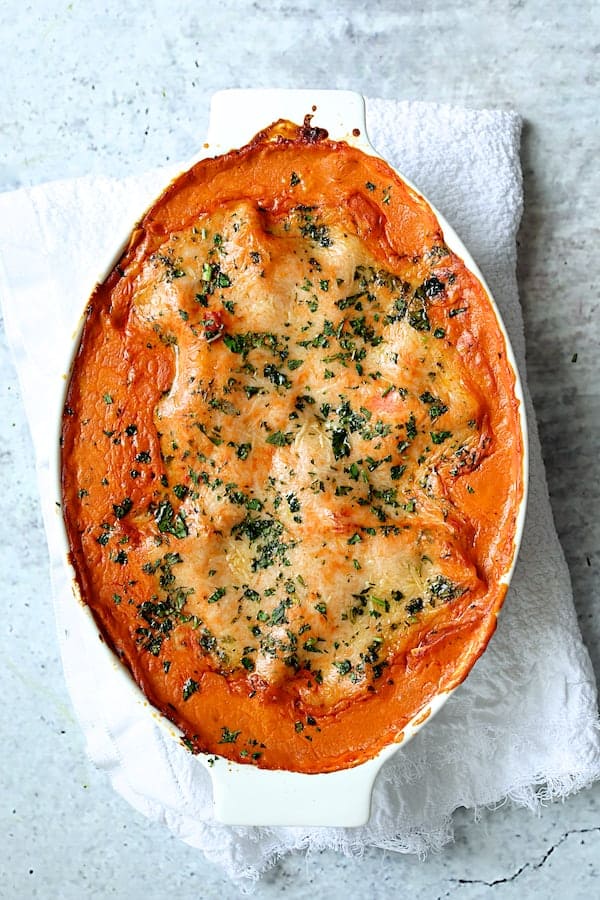 Photo of Shrimp Scallop and Artichoke Lasagna in white oval baking dish.