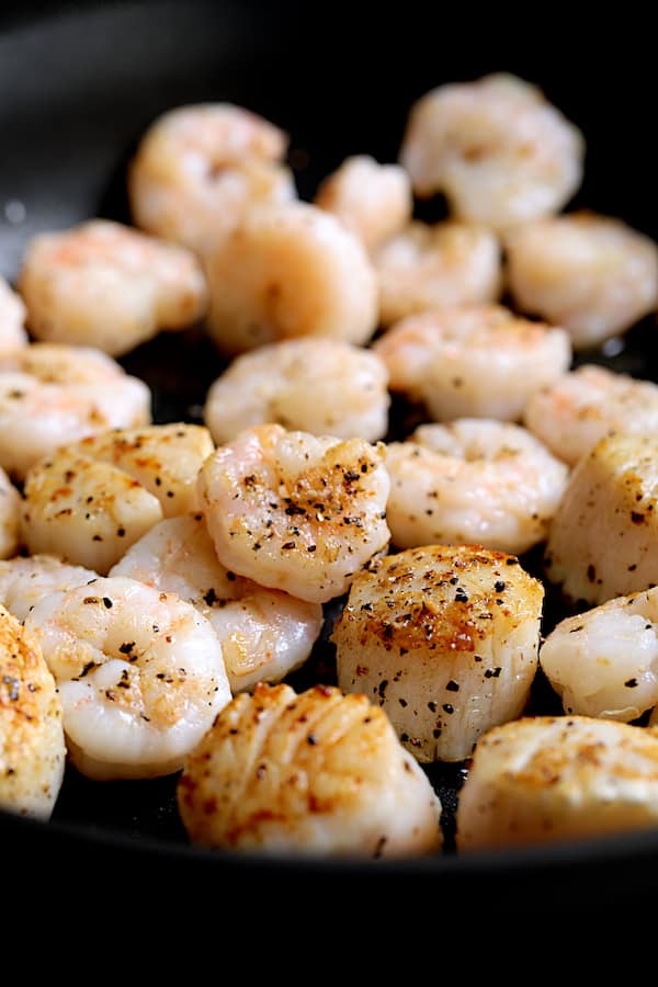 Close-up shot of seared shrimp and scallops in saute pan