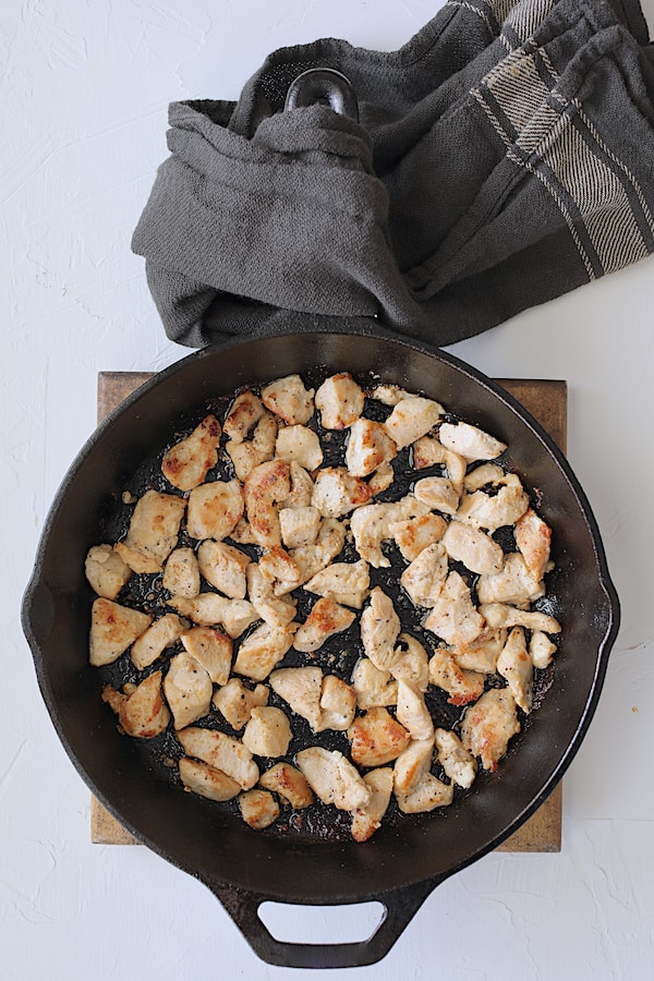 Photo of chicken pieces being browned in cast iron skillet.
