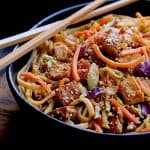 Thai Sesame Noodles with Tofu and Vegetables in black bowl with chopsticks.