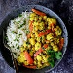One serving of Vegan Indian Cauliflower and Chickpea Curry with basmati rice in a gray bowl.