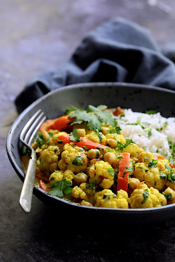 Photo of one serving of Vegan Indian Cauliflower and Chickpea Curry in gray bowl with basmati rice.