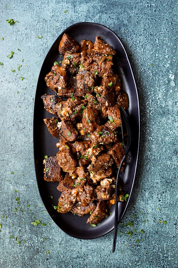 Buttery Blackened Steak Bites with Gorgonzola - Overhead shot of steak bites on black platter with cheese melted in