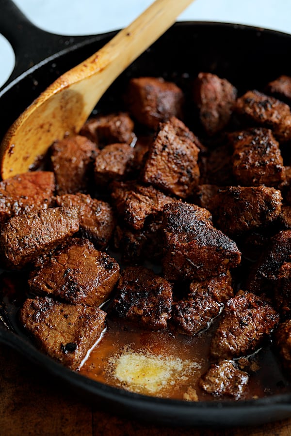 Buttery Blackened Steak Bites with Gorgonzola - Butter being added to steak bites in cast iron skillet